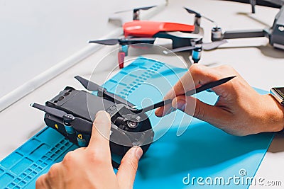 Closeup shot of man working on assembling new surveillance system using quadcopter drone with camera on table with Stock Photo