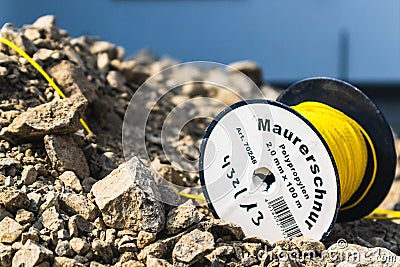 Closeup shot of masonry cord written on the yellow thread roll on the stones Editorial Stock Photo