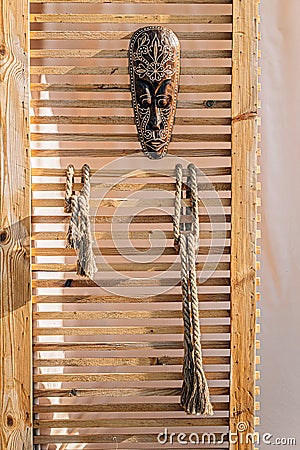 Closeup shot of an old creepy mask hanging on a wooden beach tent door Editorial Stock Photo