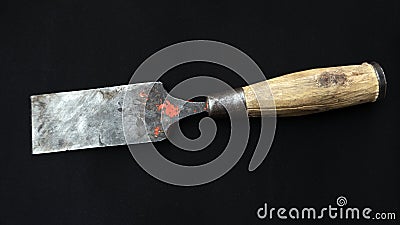 Closeup shot of an old rusty chisel with wooden handle isolated on a black background Stock Photo