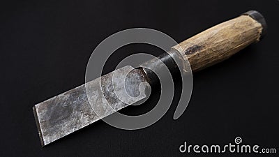 Closeup shot of an old rusty chisel with wooden handle isolated on a black background Stock Photo