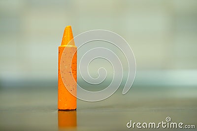 Closeup shot of an orange crayon on a reflective surface Stock Photo