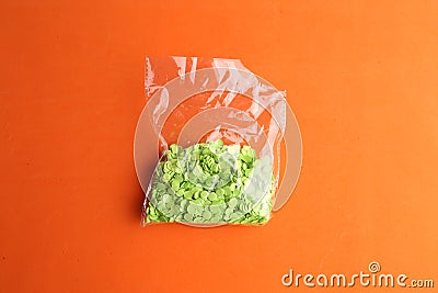 Closeup shot of packaged green round confetti on an orange background Stock Photo