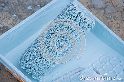 Closeup shot of a paint roller in a bucket of blue paint Stock Photo