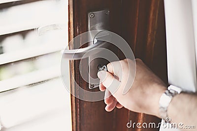 Closeup shot of a person turning the key in the lock of the wooden door Stock Photo