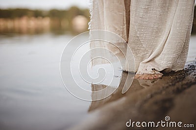 Closeup shot of a person wearing a biblical robe walking on the shoreline Stock Photo