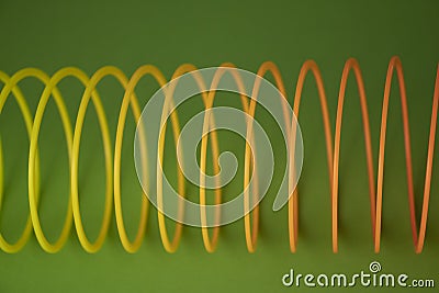 Closeup shot of plastic rainbow magic spring toy isolated on green background with copy space Editorial Stock Photo