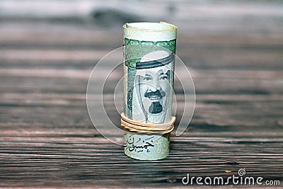 Closeup shot of a roll of 50 SAR ten Saudi riyals cash money banknote bills on a wooden table Stock Photo