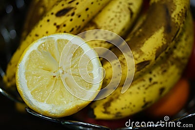 Closeup shot of a squeezed fresh lemon and a bunch of bananas Stock Photo