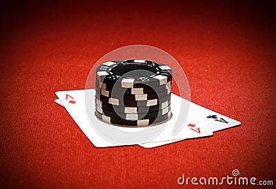 Closeup shot of a stack of casino chips on a pair of aces isolated on a red background Stock Photo