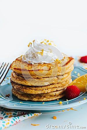 Closeup shot of a stack of healthy pancakes topped with whipped cream in a blue plate Stock Photo