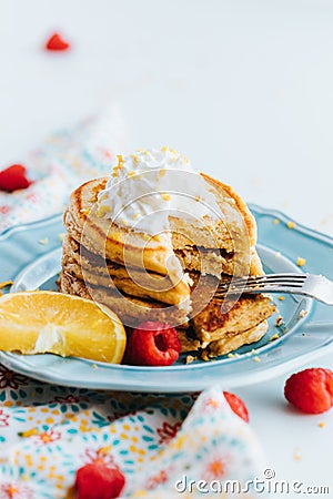 Closeup shot of a stack of healthy pancakes topped with whipped cream in a blue plate Stock Photo