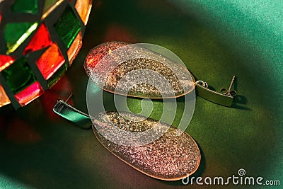 Closeup shot of stylish dangle earrings made of epoxy resin with glitter inside isolated over green background with Stock Photo