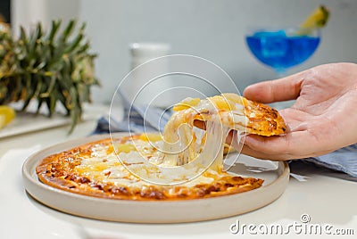 Closeup shot of unrecognizable unknown human hand picking up piece of delicious tasty Hawaiian traditional Italian crust thin Stock Photo