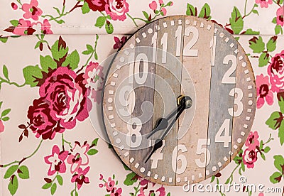 Closeup shot of a wooden clock surrounded by paintings of flowers Stock Photo