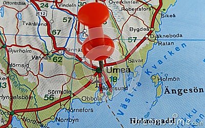 Closeup shot of a world map with a red pushpin pointing the city of Umea in Sweden Stock Photo