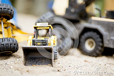 Closeup shot of a yellow bulldozer on a sandy surface with a blurred background Stock Photo