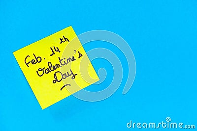 Closeup shot of a yellow romantic Valentine's Day note on a blue surface Stock Photo