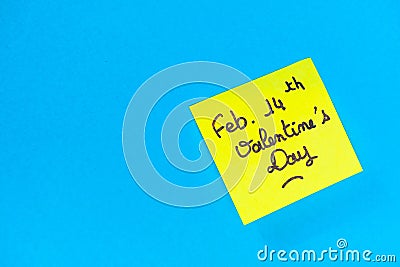 Closeup shot of a yellow romantic Valentine's Day note on a blue surface Stock Photo