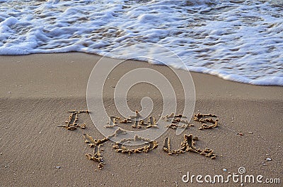 Closeup of a sign I miss you, written on sand. Wave on the beach Stock Photo