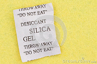 Closeup of a silica packet on yellow textured material Stock Photo