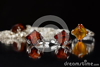 Closeup silver earrings rhombus with authentic natural baltic amber on black surface Stock Photo