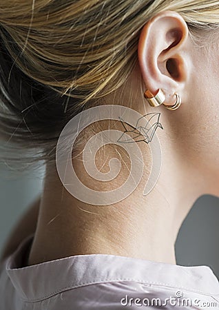 Closeup of a simple behind the ear tattoo of a young woman Editorial Stock Photo