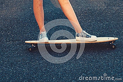 Closeup of skateboarder legs. Woman in sneakers riding skateboard outdoor. Stock Photo