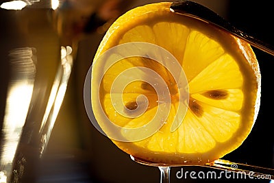 Closeup of a sliced lemon being squeezed by tongs over a dish Stock Photo