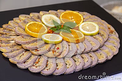 Closeup of sliced stuffed chicken roulade on a plate with orange and lemon slices Stock Photo