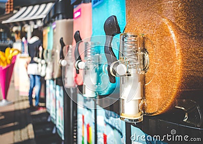 Closeup of Slush Machines with Colorful Flavors and Blurred People in the Background. Retro Style Stock Photo