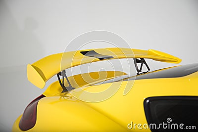 Closeup of a spoiler on a yellow modern sports car under the lights isolated on a grey background Stock Photo