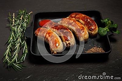 Closeup square pan with four sausages, rosemary and basil Stock Photo