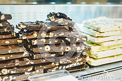 Closeup stack of assortment luxury handmade chocolate, dark and white chocolate bars with nuts in shop window. Stock Photo