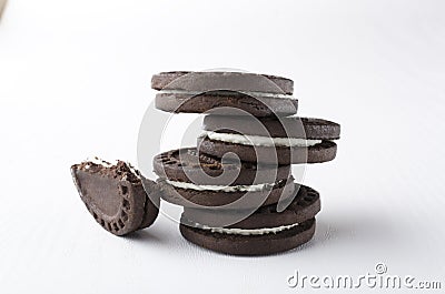 Stack of dark sandwich cookies and piece of it on the white background Stock Photo
