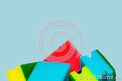 Close-up of a stack or heap of various colorful sponges or scouring pads isolated on a blue background. Household chore concept. Stock Photo