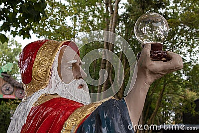 Closeup of a Statue of a wizard holding a glass bowl in his hand, in a theme park, France Stock Photo