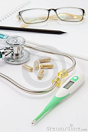 Closeup a stethoscope, thermometer, pills, notepad, pen and glasses on doctor table Stock Photo