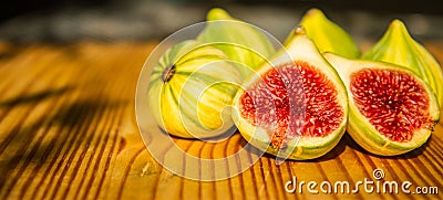 Closeup still life of group of whole panachee variegated striped figs on brown wooden cutting board with one fig sliced in half in Stock Photo