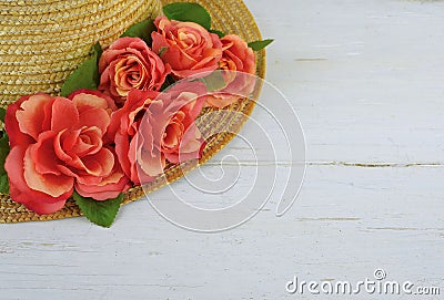 Closeup of a straw bonnet decorated with multiple silk roses on a white washed wooden background with copy space. Good for spring Stock Photo