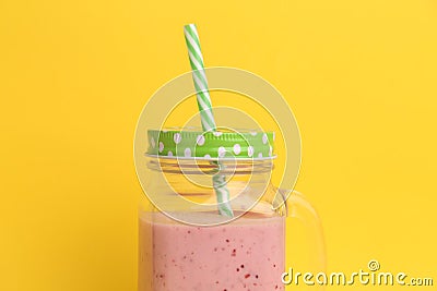 Closeup of a strawberry smoothie inside an aesthetically cute mason jar mug with green cap and straw Stock Photo