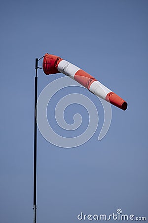Closeup of striped windsock waiving in the wind against bright blue sky Stock Photo