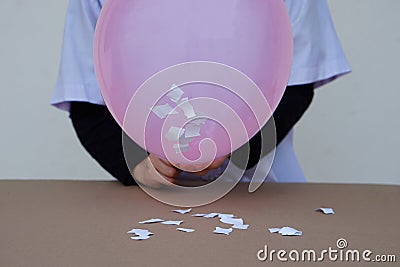 Closeup student do science experiment about static electricty from pink balloon and pieces of paper. Stock Photo