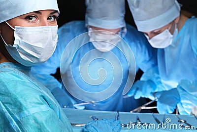 Closeup of surgeons performing operation. Focus on female nurse. Medicine, surgery and emergency help concepts Stock Photo
