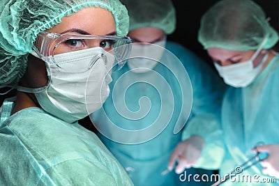 Closeup of surgeons performing operation. Focus on female nurse. Medicine, surgery and emergency help concepts Stock Photo