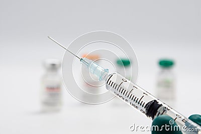 Closeup syringe with vaccine against covid-19 on blurred background of vial with coronavirus vaccine. Stock Photo