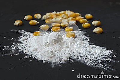Closeup of tapioca starch or powder flour with maize grains on a black background. Corn starch with yellow grains on a Stock Photo