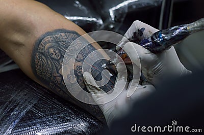 Closeup of a tattoo artist giving a tattoo in a studio under the lights Editorial Stock Photo