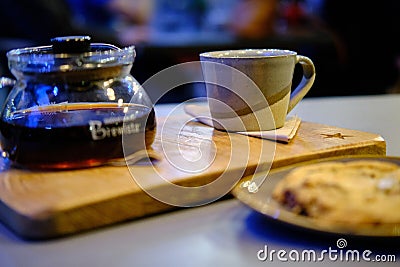 Closeup of a teapot with a cup on the table under the lights with a blurred background Editorial Stock Photo