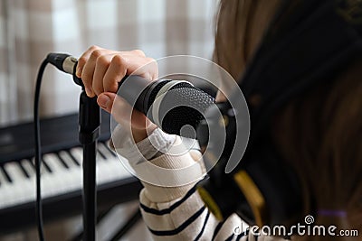Closeup of teenager recording music in home studio. Girl with headphones and microphone recording song Stock Photo